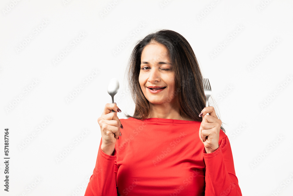Indian thoughtful lady rising fork knife looking empty space isolated white color background Indian thoughtful lady rising fork knife looking empty space isolated white color background