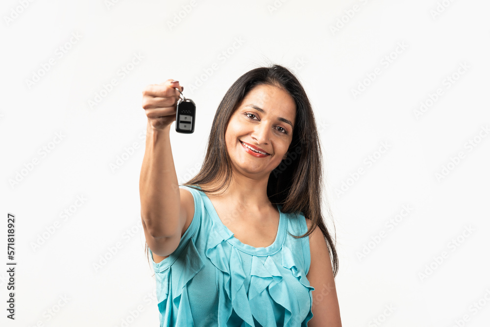Mid aged Indian woman giving showing close up car key isolated on white background Mid aged Indian woman giving showing close up car key isolated on white background