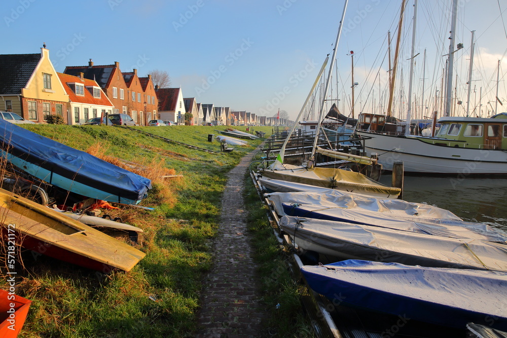 Naklejka premium The village of Durgerdam, North Holland, Netherlands, located near Amsterdam along the dyke of the IJmeer (IJ lake), with colorful wooden houses and boats. Picture taken in winter after sunrise.