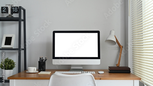 White blank screen computer monitor, lamp, coffee cup and books on working table. Modern workplace © Prathankarnpap