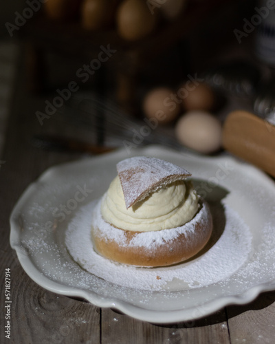Semla on a white porcelain dish with plenty of icing sugar on top