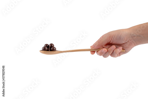 Chocolate balls on wooden spoon in hand on transparent background.