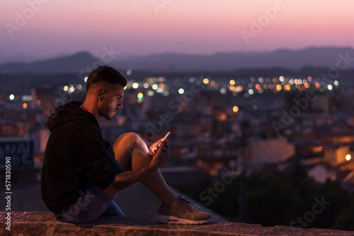 Man is looking his smartphone at night, lights of the city are o photo