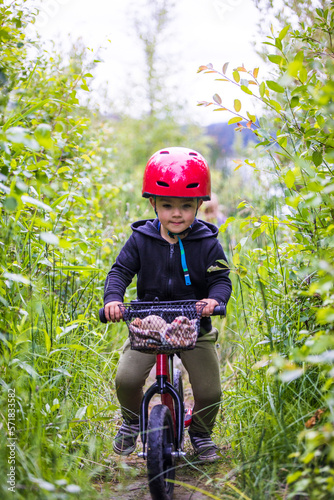 Toddler boy riding balance bike through forest. photo