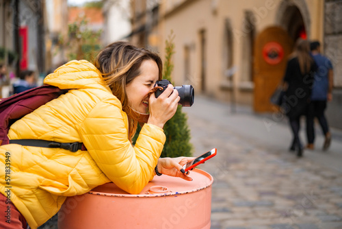 Young tourist woman with a camera smartphone taking pictures outdoors photo
