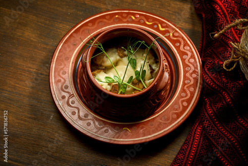 Ukrainian dumplings stuffed with meat in a clay pot. Wooden table © ismishko