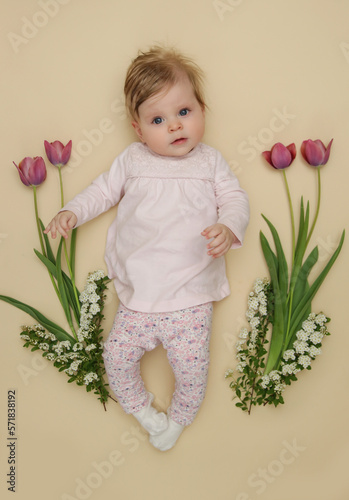 Adorable five months old baby with pink spring tulips. Herald of spring. Baby and infant milestone session. Spring composition. Photoshoot of newborns. March 8 or Easter postcard concept. photo