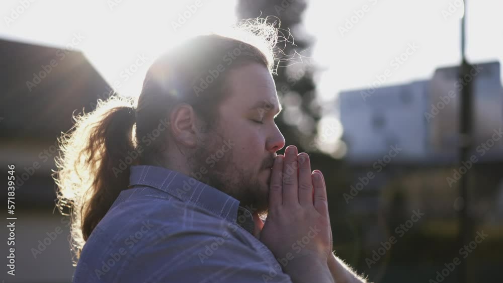 Spiritual young man praying to GOD outdoors in sunlight. A male