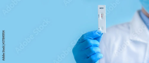 Fotografie A doctor wearing protective mask and gloves shows a rapid laboratory test for hepatitis C virus (HCV)