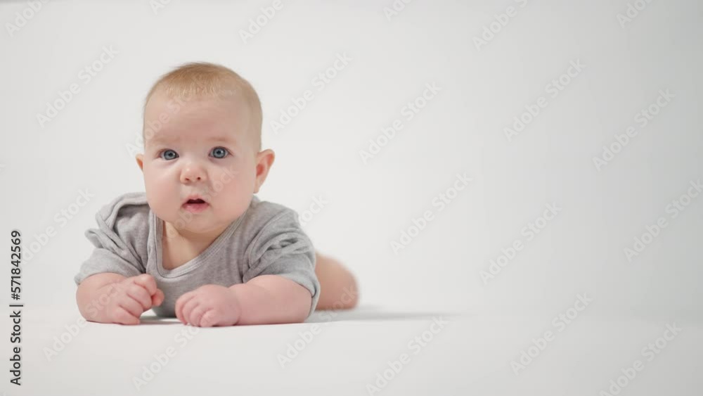 Portrait of a baby. A baby lying on his stomach in close-up against a white background, looking at the cameraman