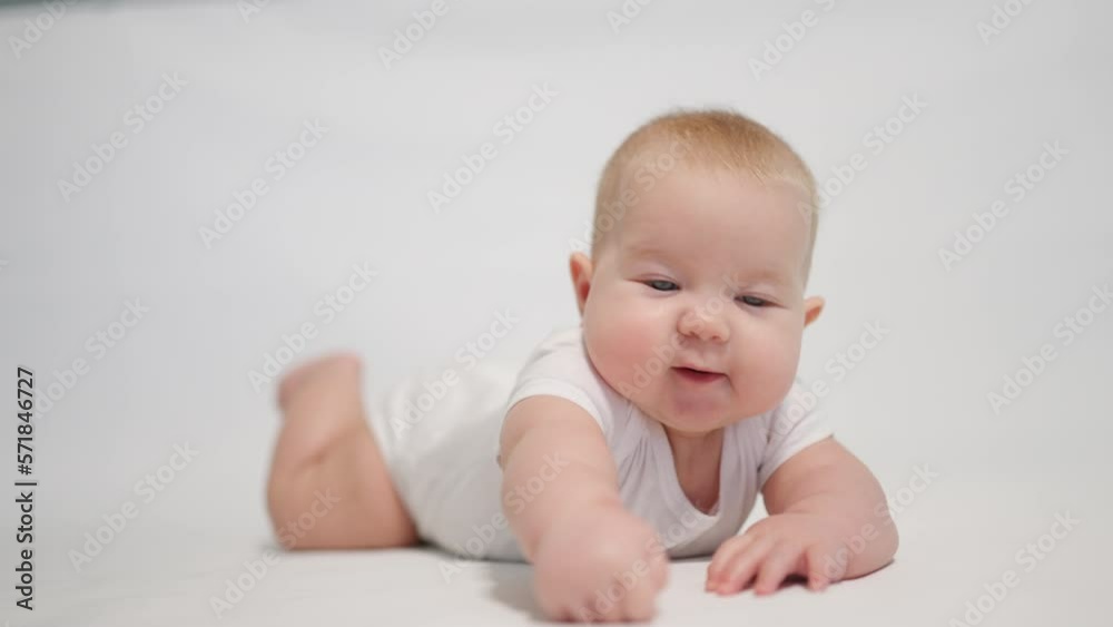 Close-up of the baby with positive emotion. on the white background, the first reflexes to uprightness Close-up of the baby with positive emotion. on the white background, the first reflexes to uprightness