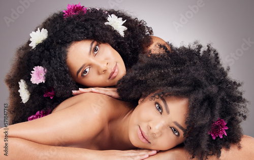 Portrait of black women, hair care and friends with flowers in studio isolated on gray background. Floral cosmetics, organic makeup or face of female models with plant for beauty skincare or wellness