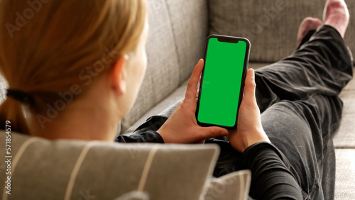 Woman Holding a Vertical Green Screen Smartphone, Lying on the Couch