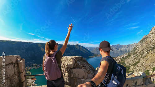 A couple taking selfies with scenic view from St Ivan fortress on Kotor bay in summer, Adriatic Mediterranean Sea, Montenegro, Balkans, Europe. Fjord winding along coastal towns. Travel destinations
