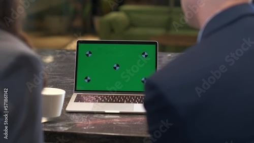 Man and a woman in suits sit at a table and actively discuss what they saw on the green screen of a laptop. Business meeting over a cup of tea or coffee. Close-up shot. Emphasis on gesticulating hands