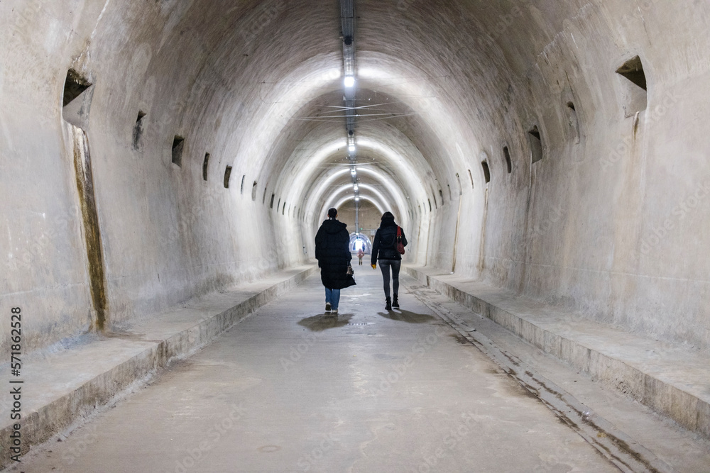 person walks through an abandoned tunnel that was built during World War II. the clothes are winter
