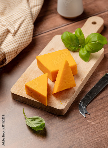 Cheddar orange cheese triangles, wooden background