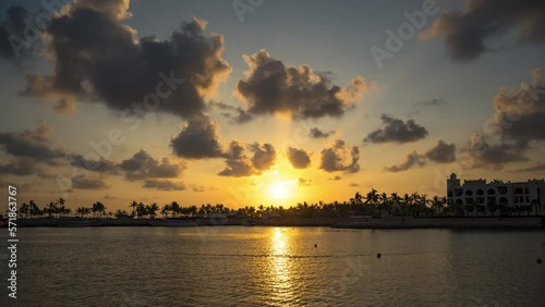 Timelapse of moving clouds, sun and palm trees at a beach in Salalah, Oman