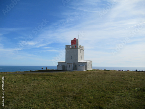 Dyrhólaey Lighthouse in Iceland with sea, blue sky and white clouds on the background