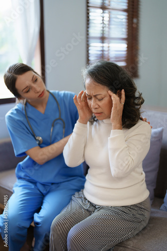 Portrait of a female doctor talking to an elderly patient showing headache.