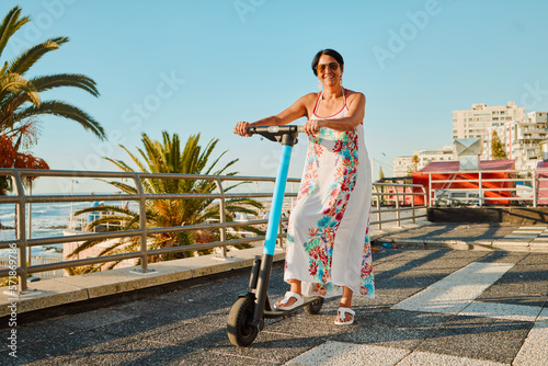 Electric scooter, retirement and smile, woman on summer ride at tropical island beach resort for happy vacation. City, street and eco friendly transport, fun grandma on escooter on holiday in Hawaii. photo