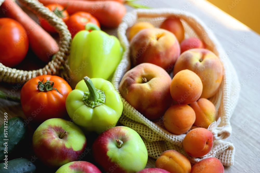 Straw bag and reusable fabric bags filled with various healthy fruit and vegetables. Wooden background, selective focus. Straw bag and reusable fabric bags filled with various healthy fruit and vegetables. Wooden background, selective focus.