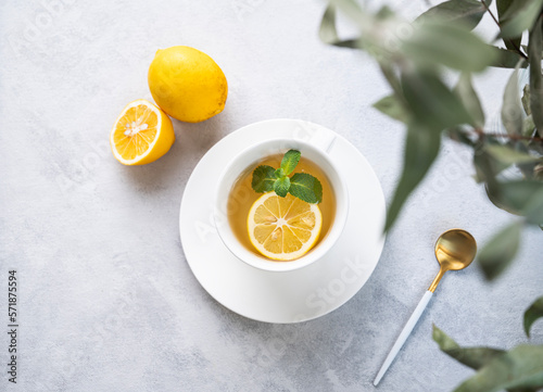 Herbal tea with lemon and mint in a white cup on a light background with eucalyptus branches close up. The concept of a healthy and delicious breakfast drink for immunity.