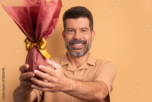 joyful mature man celebrating easter egg gift in beige background. holiday, easter, celebration concept.