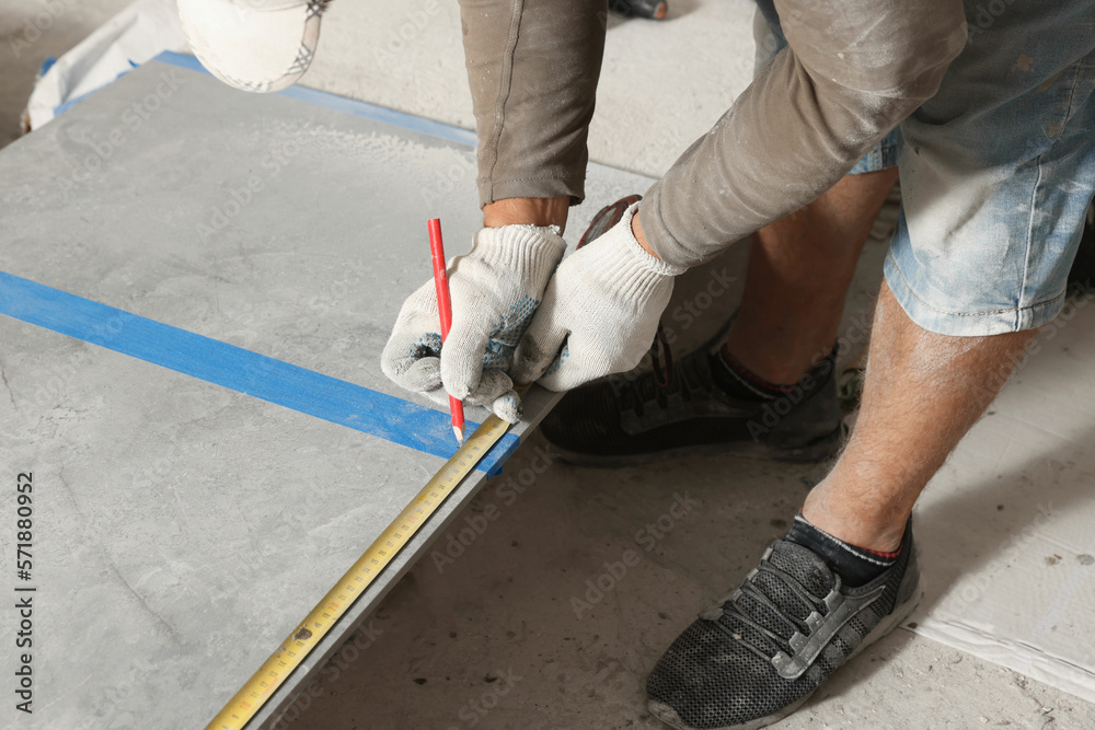 Worker measuring tiles for installation, closeup view Worker measuring tiles for installation, closeup view