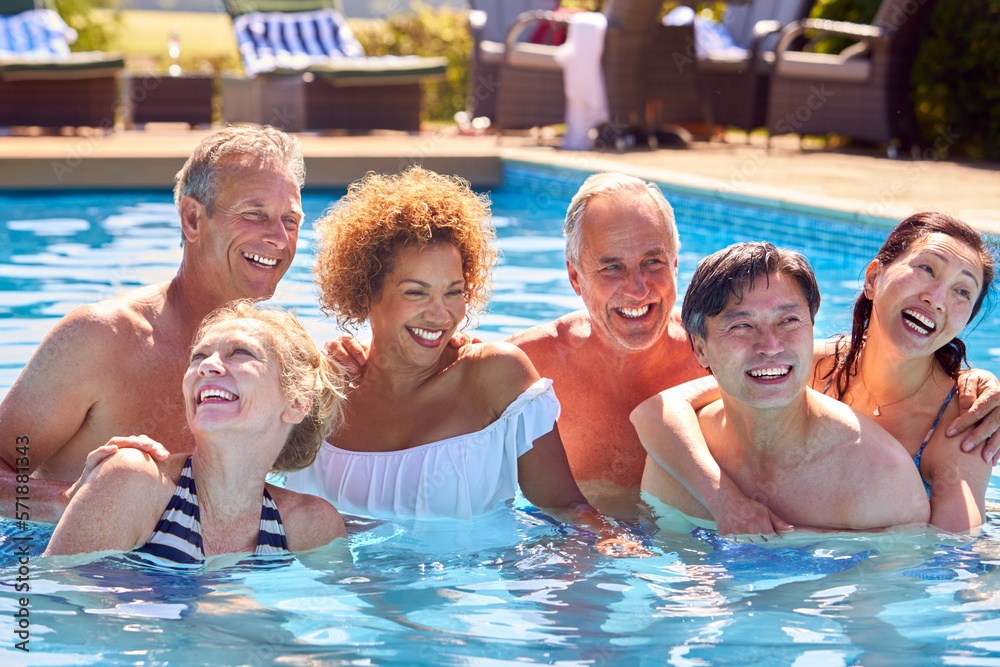 Portrait Of Multi-Cultural Group Of Senior Friends Relaxing In Outdoor Pool On Summer Vacation