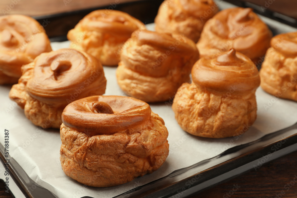 Delicious fresh profiteroles on baking pan, closeup Delicious fresh profiteroles on baking pan, closeup