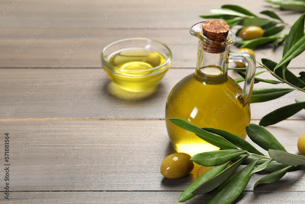 Jug of cooking oil, olives and green leaves on wooden table. Space for text Jug of cooking oil, olives and green leaves on wooden table. Space for text