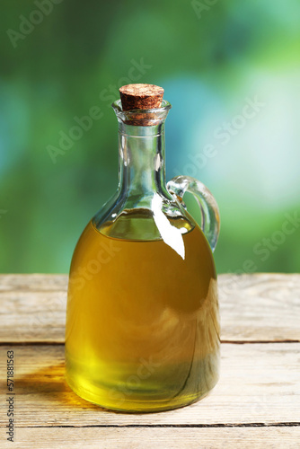 Jug of olive oil on wooden table against blurred background