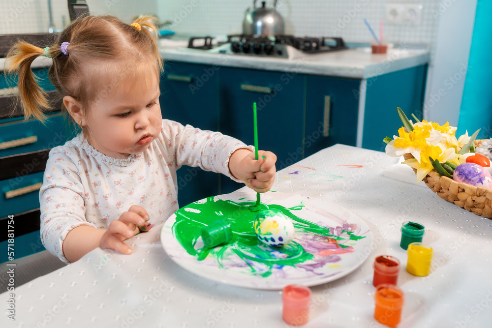 Portrait of cute caucasian toddler girl paintings egg to the Easter. Home celebration Portrait of cute caucasian toddler girl paintings egg to the Easter. Home celebration