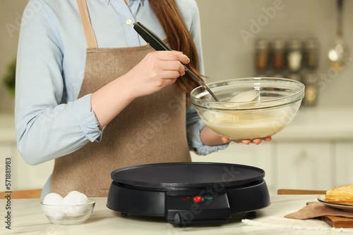 Woman with dough for crepes at white marble table in kitchen