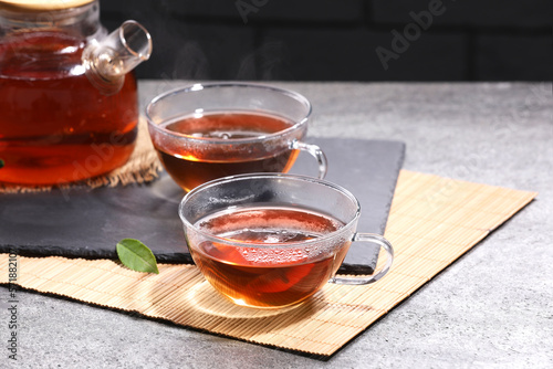 Aromatic hot tea in glass cups and teapot on light grey table