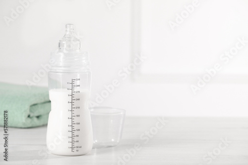 Feeding bottle with milk on white wooden table. Space for text photo