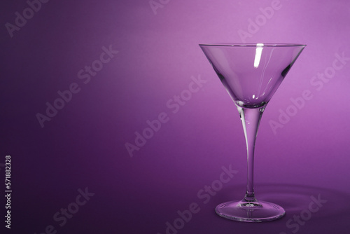 Elegant empty martini glass on purple background. Space for text