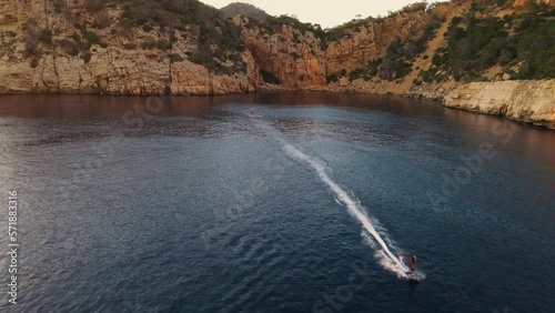 drone footage of someone surfing away from the shoreline on a fliteboard photo