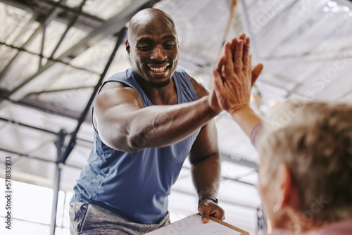 Fitness, gym and man high five for senior support, personal trainer goals and exercise progress. Workout, success and elderly person with black man for achievement and hands together sign in training