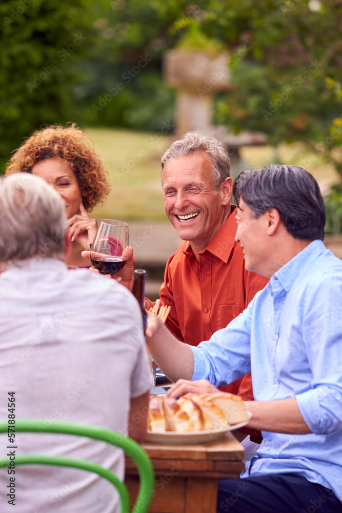 Group Of Mature Friends Talking Around Table At Summer Dinner Party In Garden At Home Group Of Mature Friends Talking Around Table At Summer Dinner Party In Garden At Home