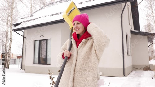 Portrait of a girl with a shovel in winter on the background of a house