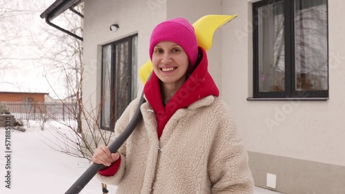Portrait of a girl with a shovel in winter on the background of a house