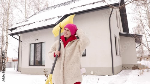 Portrait of a girl with a shovel in winter on the background of a house