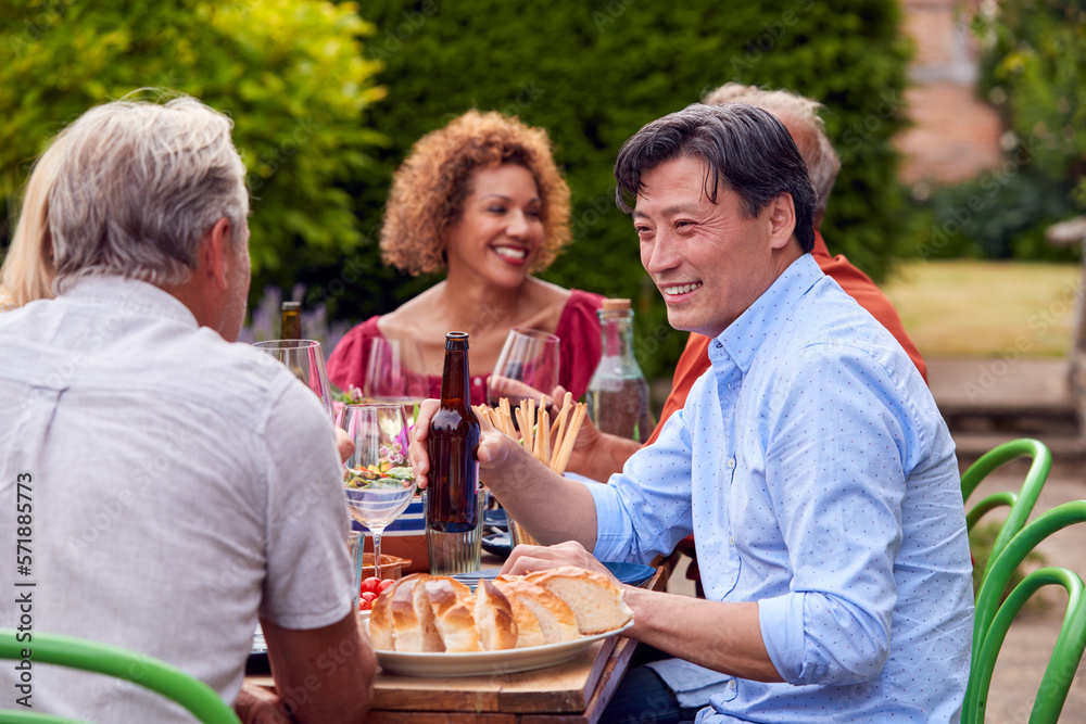 Group Of Mature Friends Talking Around Table At Summer Dinner Party In Garden At Home Group Of Mature Friends Talking Around Table At Summer Dinner Party In Garden At Home