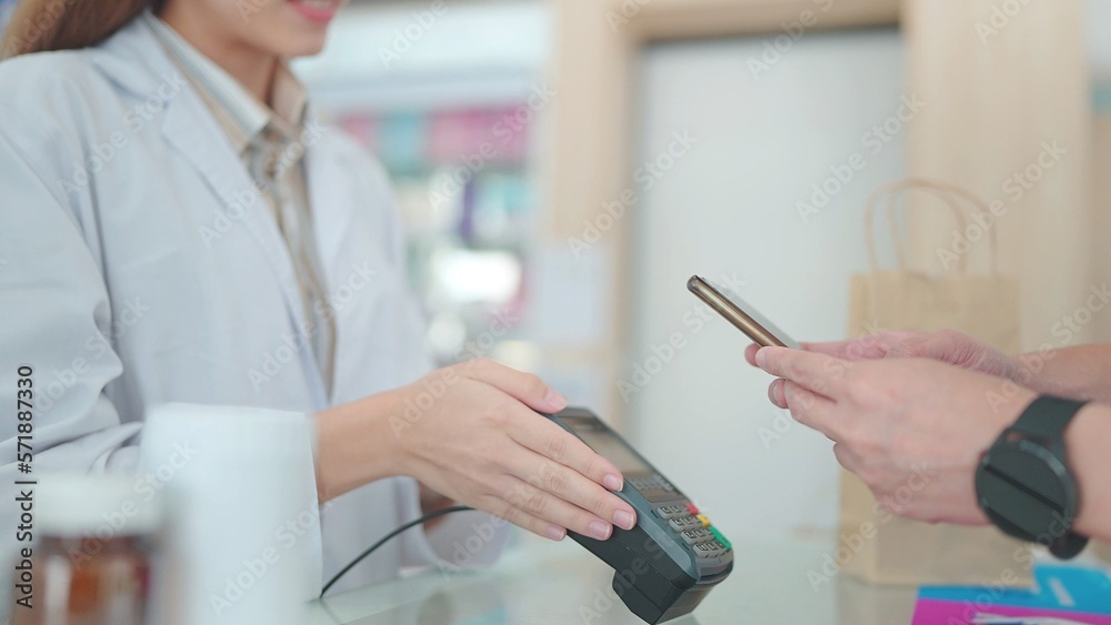 Fototapeta premium A customers buy medicines with pharmacists in drugstores and scan barcodes to payments