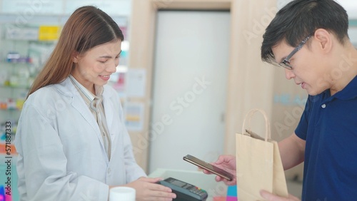 Asian male customers buy medicines with pharmacists in drugstores and scan barcodes to payments © M Stocker