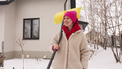 A beautiful girl with a shovel goes to snow removal