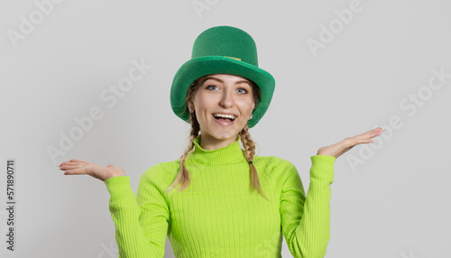 St. Patrick's Day leprechaun model girl in green hat, funny clover shaped sunglasses, isolated on white background and smiling, having fun. Patrick Day pub party, celebrating.