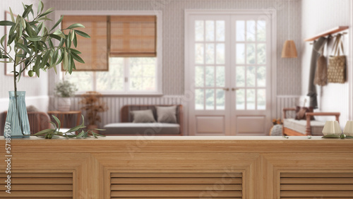 Wooden table top, cabinet, panel or shelf with shutters close up. Olive branch in vase and candles. Blurred background, scandinavian living room with rattan sofa, interior design © ArchiVIZ